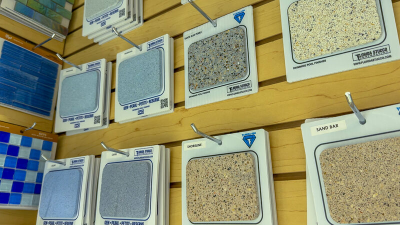 Pebble and aggregate pool finish samples in blue and neutral tones